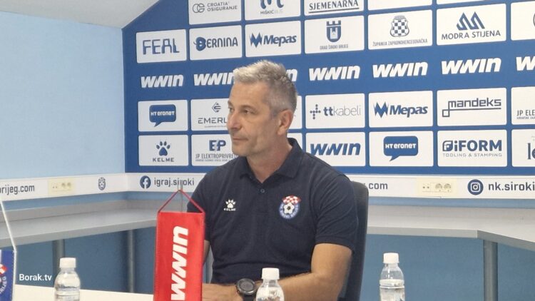 Igrači Širokog Brijega i Posušja bore se za loptu na natopljenom terenu stadiona Pecara, dok jaka kiša pada tijekom utakmice.